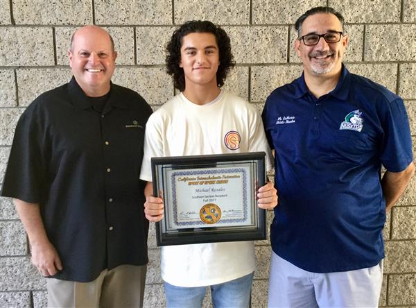 Photo of two adult men, flanking a high school male student who is holding a plaque Photo of two adult men, flanking a high school male student who is holding a plaque